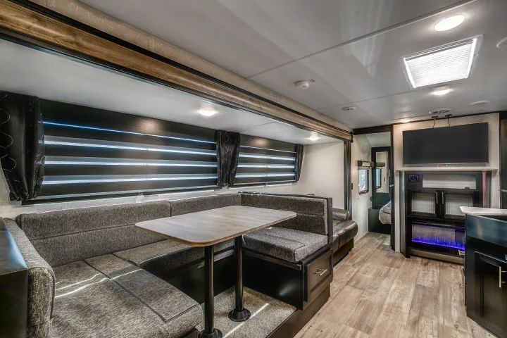 Modern RV rental interior: comfortable dinette, living area with TV & fireplace. Ideal for road trips.. Cherokee Grey Wolf 2022
