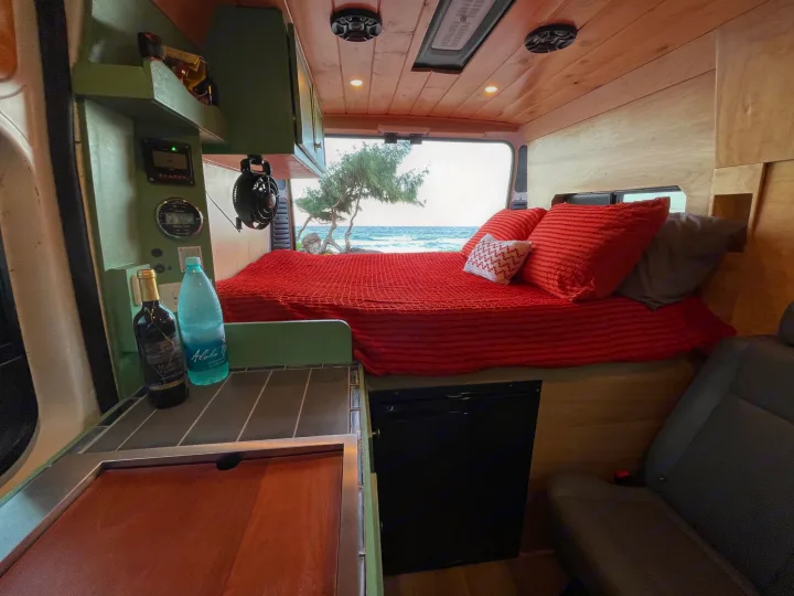 Stunning RV rental interior with an ocean view bed, kitchenette, and fridge. Perfect for a relaxing adventure.. Dodge Ram Promaster 1500 2021