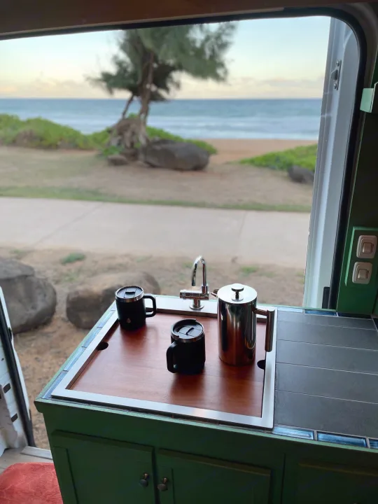 Enjoy coffee with an ocean view from this RV rental. A French press, two mugs, and a sink are on the counter.. Dodge Ram Promaster 1500 2021