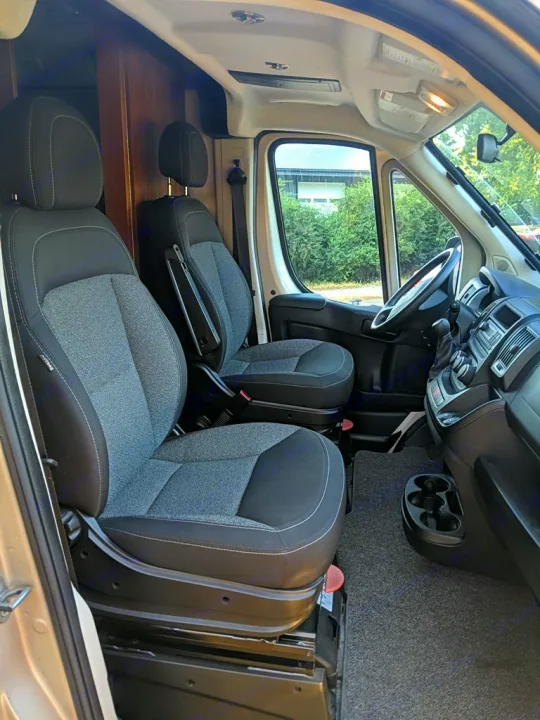 RV rental interior: front swivel seats, rear seating, and a built-in wooden table for travel convenience.. Roadtrek Roadtrek Class B 2017