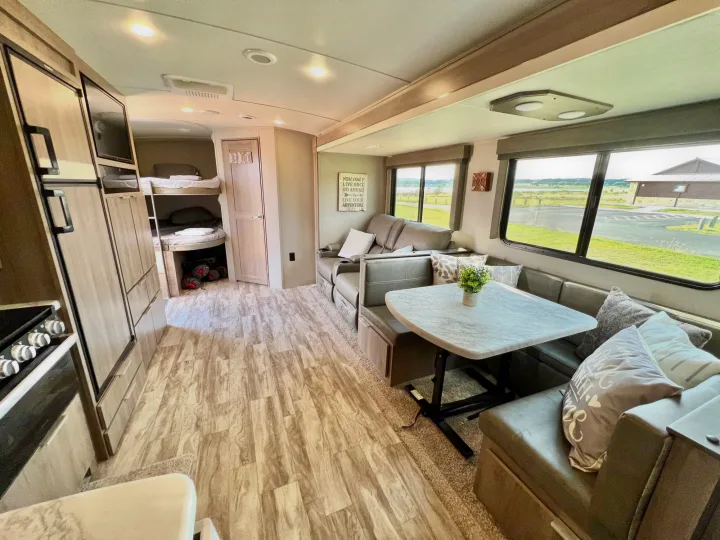 Spacious RV rental interior featuring a living area, dining booth, kitchen, and bunk beds. Ideal for family travel.. Grand Design Imagine 2021