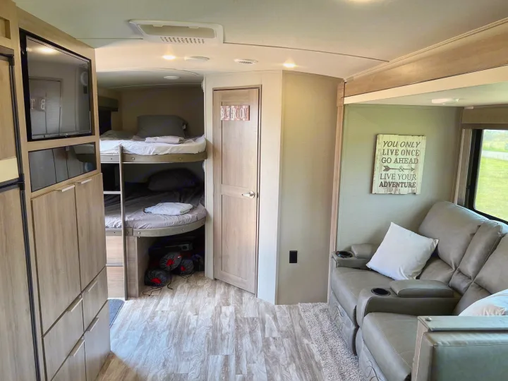 **RV rental interior:** Bunk beds, TV, and recliners create a comfy living space with ample storage.. Grand Design Imagine 2021