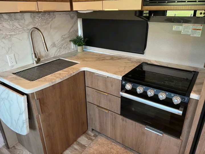RV rental kitchen: Modern design with marble counters, stainless sink, stove, and wood cabinets. Great for your next adventure.. Grand Design Imagine 2021