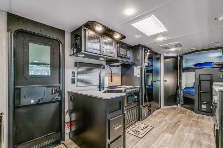 Spacious RV rental interior featuring a modern kitchen, bunk beds, and a welcoming entry. Ideal for family trips.. Cherokee Grey Wolf 2022