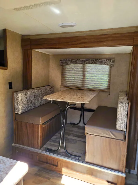 Cozy RV rental dinette with comfortable bench seating, a functional table, and a window for natural light.. Forest River Viking 2018