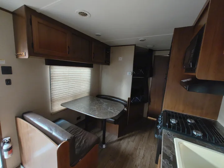 RV rental interior: dinette seating, kitchen with stove and sink, and built-in bunk beds.. Jayco Jay Flight SLX 2016
