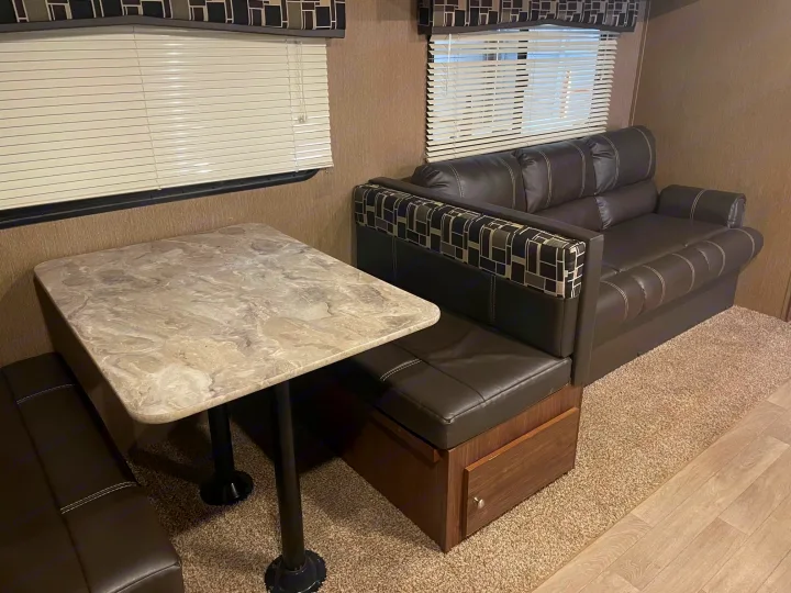Inside an rv rental: a cozy dinette with faux leather benches and a sofa bed, offering comfort on the go.. Dutchmen Coleman Lantern 2017