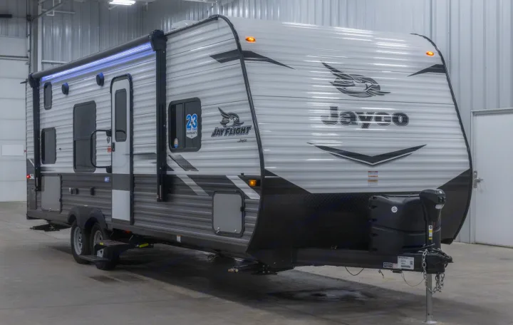 Brightly lit, modern Jayco travel trailer, ideal for RV rental adventures. Features an illuminated awning.. Jayco Jay Flight SLX 2022
