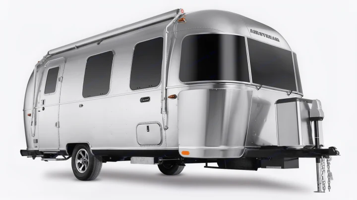 A shiny, modern Airstream travel trailer, with large black windows, ready for your next rv rental adventure.. Airstream Caravel 2022