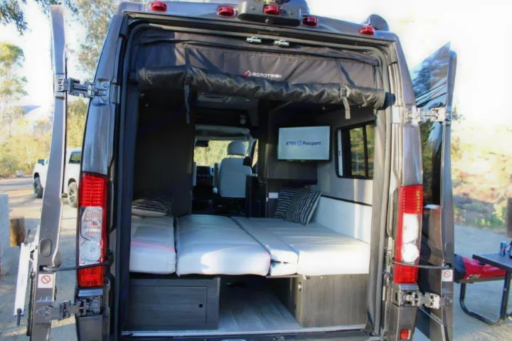 Rear view of a modern camper van's interior. This RV rental features a comfortable bed, TV, and versatile mobile living space.. Roadtrek Zion 2022
