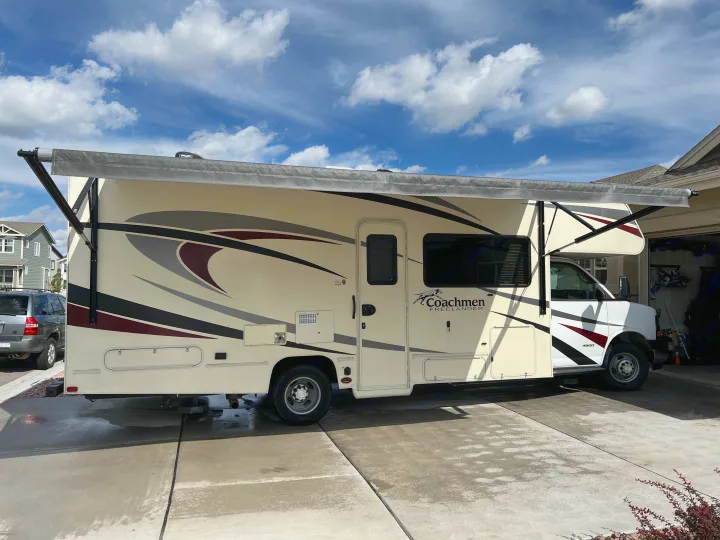 Cream-colored Coachmen Freelander RV with extended awning, great for an rv rental, parked on a wet driveway.. Forest River Coachmen Freelander 2019