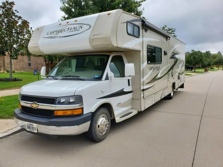White and tan Coachmen Leprechaun Class C RV rental. This spacious motorhome is parked on a residential street.. Coachman Leprechaun 2014