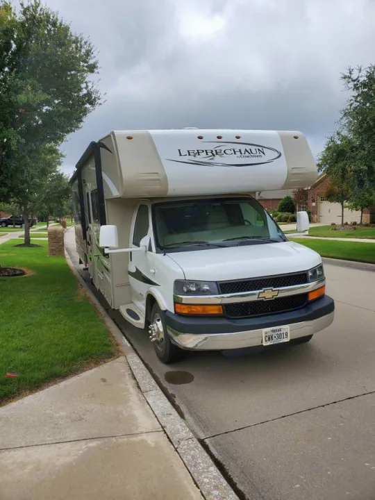 A white Leprechaun Class C RV rental parked on a quiet suburban street, ready for your next travel adventure.. Coachman Leprechaun 2014