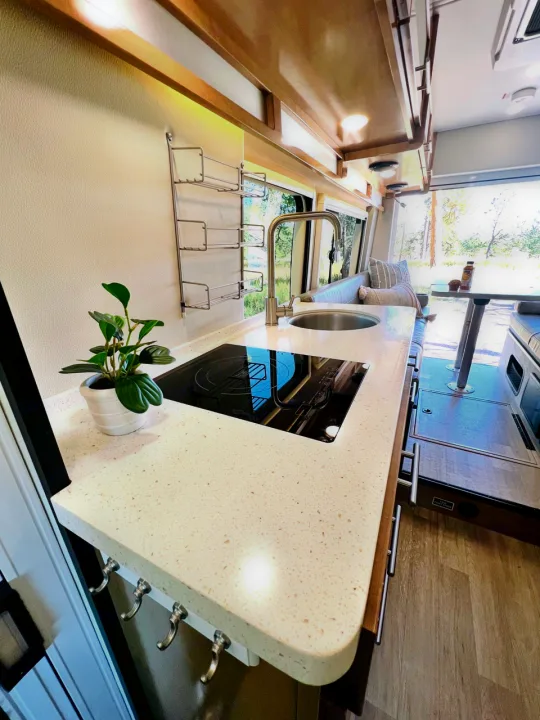 This modern RV rental features a well-appointed kitchen with a sleek countertop, sink, and stovetop, plus a cozy dining area.. Coachmen Beyond 22D 2020