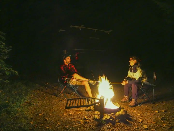 Two people roast marshmallows by a campfire, with an RV rental visible in the background, making for a cozy night.. Chevrolet silverado 2500 2022