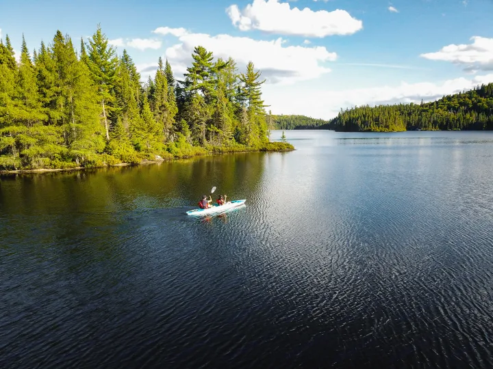 Kayaking on a peaceful lake framed by green forests under a blue sky, perfect for your RV rental adventure.. Chevrolet silverado 2500 2022