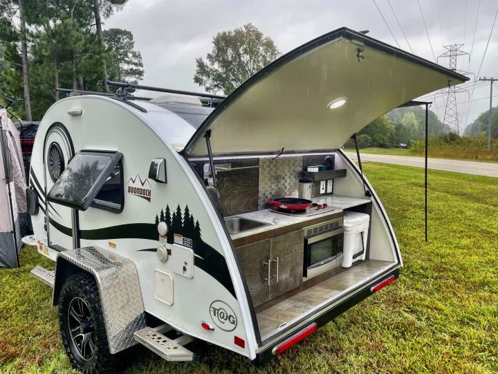This T@G Boondock rv rental features an impressive rear outdoor kitchen with a sink, stove, and microwave.. nuCamp T@G 2021