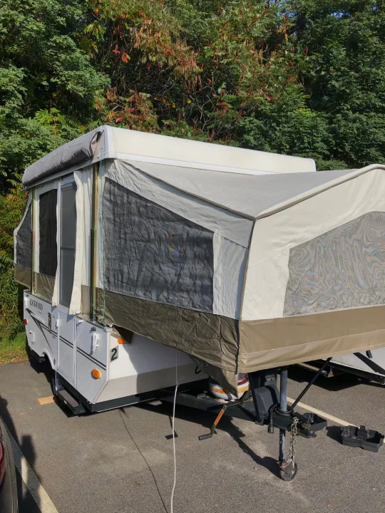Ready for adventure: a pop-up camper RV rental fully set up, showcasing its extended canvas and mesh windows for outdoor living.. Forest River Rockwood LTD 2010