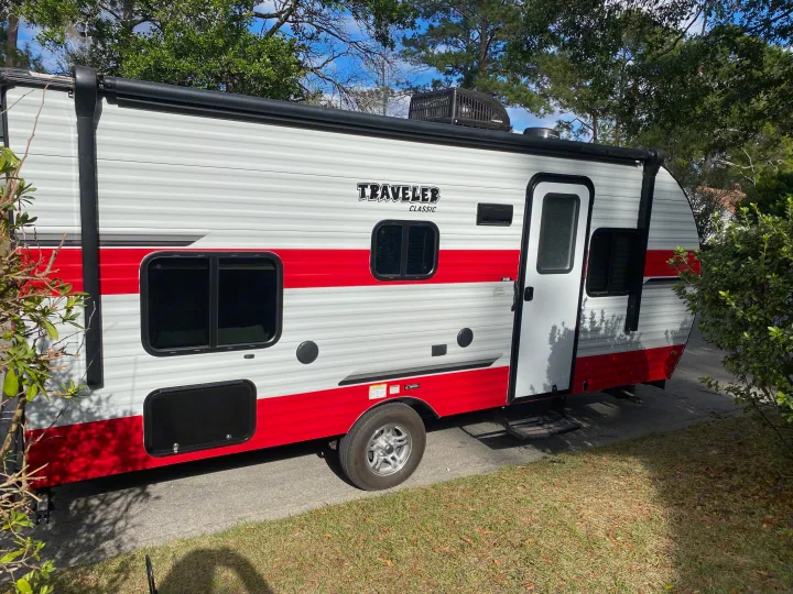 Bright red and white Traveler Classic RV rental, featuring a Dometic AC unit, parked on pavement.. Sunset Park RV Sun Lite 2020