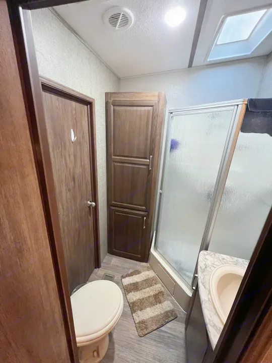 Clean RV rental bathroom featuring a toilet, shower, sink, and storage, ideal for your travels.. Keystone RV Cougar 2017