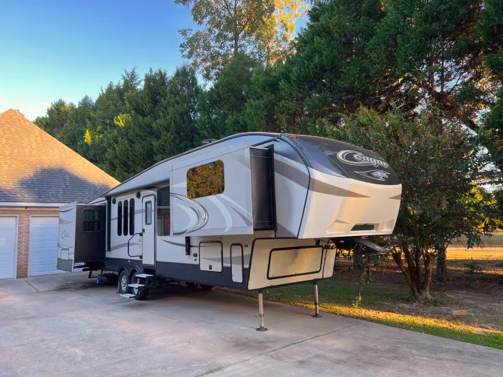 Spacious fifth-wheel RV rental parked on a driveway, ready for adventures or temporary living.. Keystone RV Cougar 2017