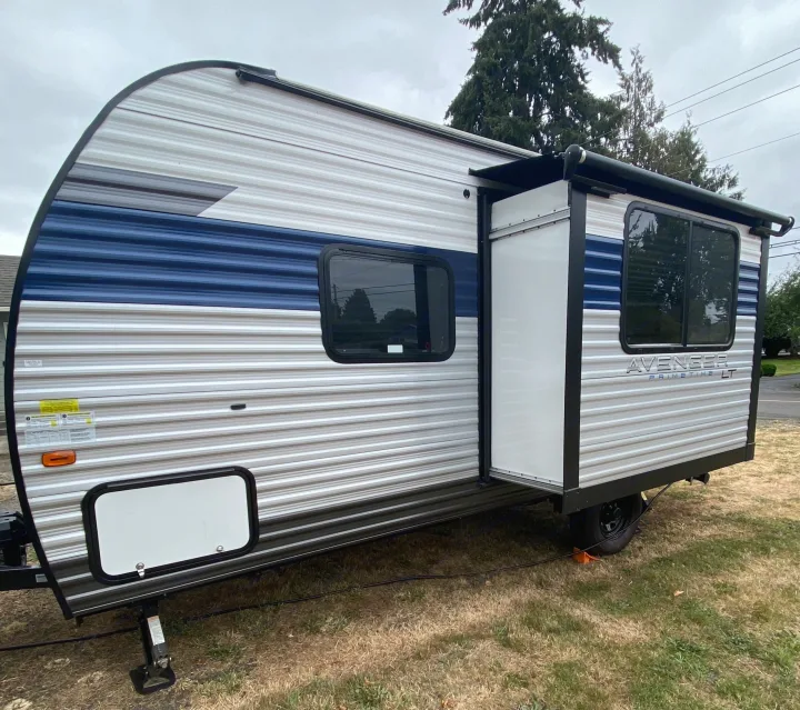 Modern Avenger RV rental with extended slide-out and awning, parked on grass.. Forest River Avenger 2022