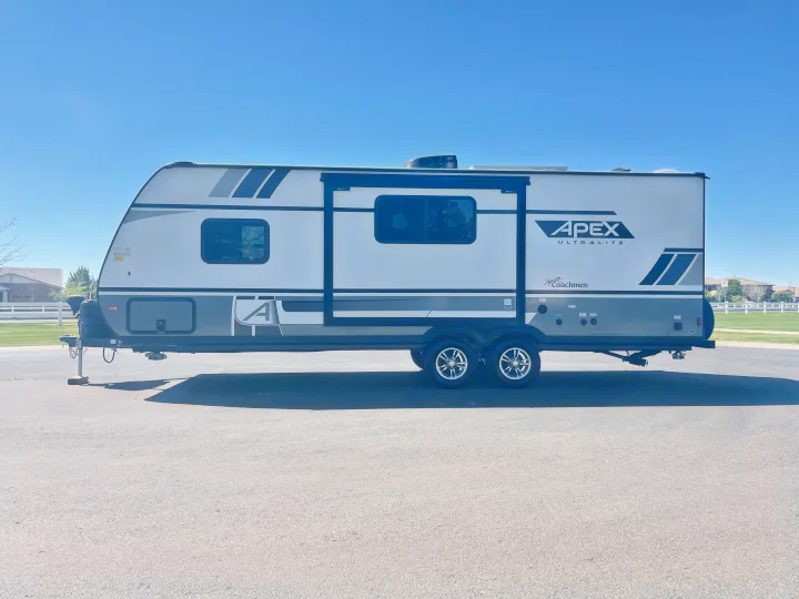 This modern Apex travel trailer, an excellent rv rental option, is ready for adventure under a clear blue sky.. Coachmen Apex 2022
