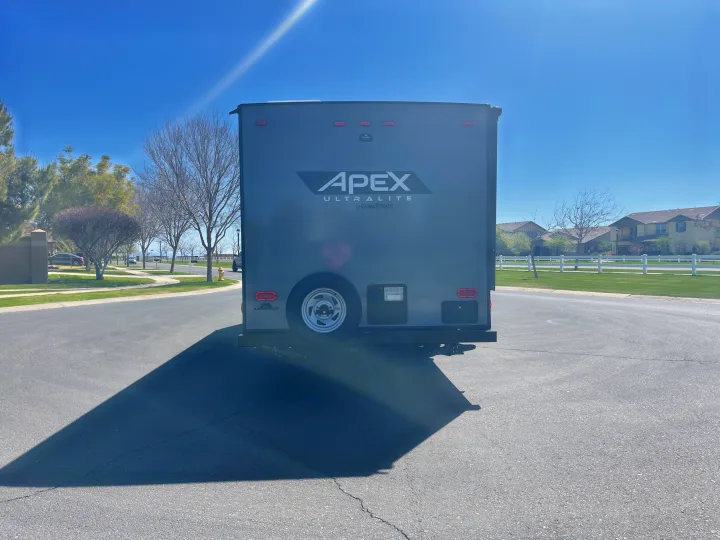 Rear view of a grey Apex Ultralite travel trailer, a great RV rental option, parked on a sunny street.. Coachmen Apex 2022
