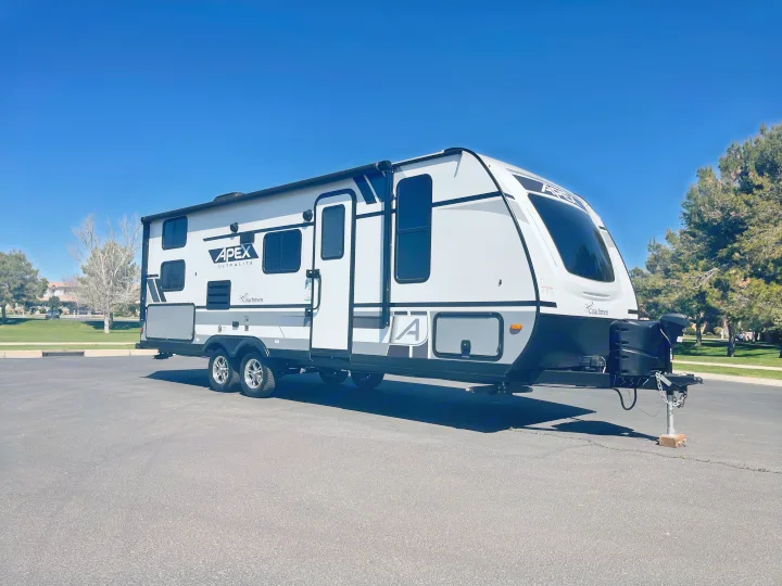 This Apex Ultralite RV rental is neatly parked on asphalt under a clear blue sky, ready for its next adventure.. Coachmen Apex 2022