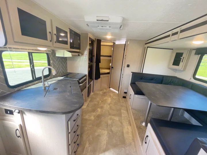 Spacious RV rental interior featuring a modern kitchen, dining area, and bunk beds for comfortable travel.. Coachmen Apex 2022