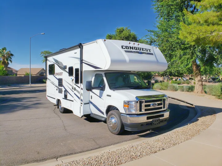 Clean white Conquest Gulf Stream motorhome (RV rental) parked on a sunny residential street, ready for your next trip.. Gulf Stream Conquest 2022