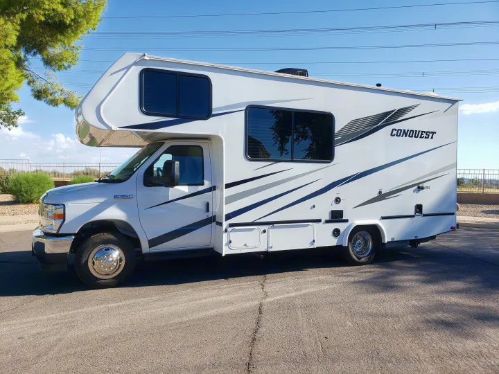 White Ford E-350 Class C RV for rent, with sleek grey graphics, parked outdoors on a bright day.. Gulf Stream Conquest 2022