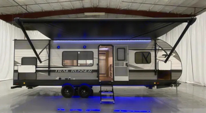 A sleek travel trailer RV with an extended awning and blue LED lights, ready for your next rv rental adventure.. Heartland RVs Trail Runner 2020