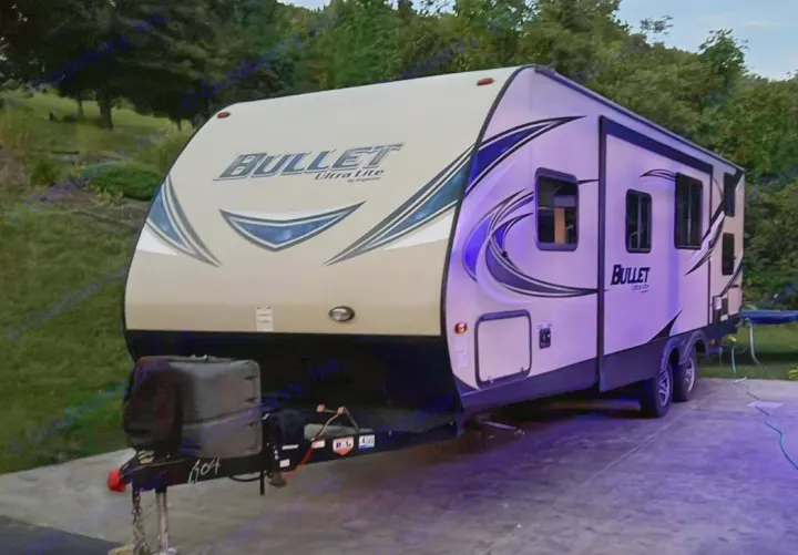 This 'Bullet Ultra Lite' travel trailer, glowing with purple light at dusk, is ideal for your next RV rental adventure.. Keystone RV Bullet Ultra Lite 2016