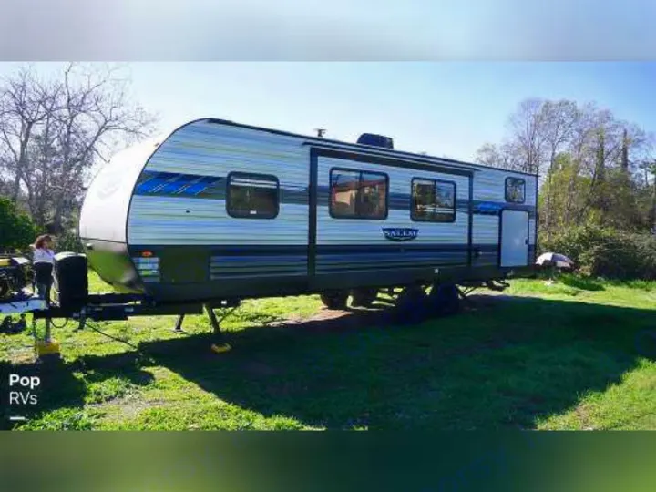 A modern Salem travel trailer, white with blue and gray stripes, is parked on green grass, perfect for an RV rental adventure.. Forest River Salem 2020