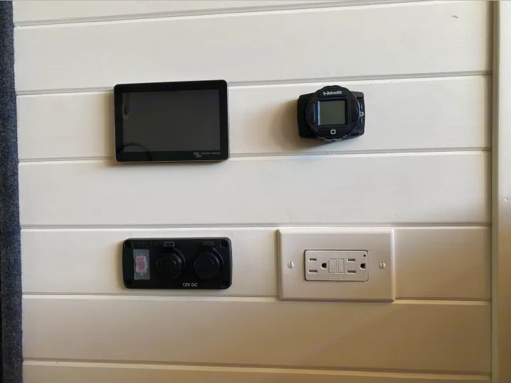 RV rental interior featuring a Victron monitor, Webasto heater control, 12V DC, and 120V AC outlets for power management.. Ford Transit 2019