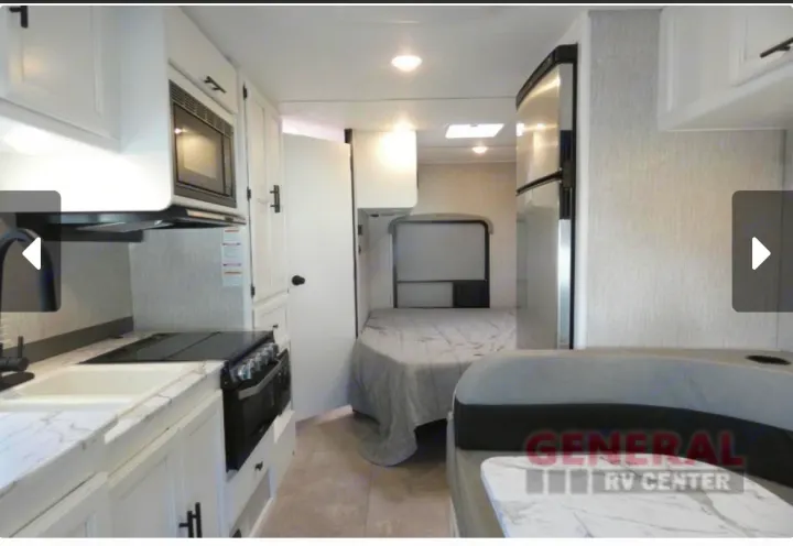Step inside this modern RV rental: a compact living space featuring a full kitchen, a comfortable bed, and dining booth.. Coachmen Cross Trail 2022
