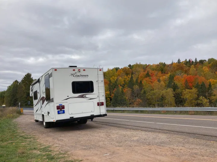 RV rental parked by a road, showcasing vibrant fall foliage and cloudy skies, perfect for an autumn road trip stop.. Coachman Freelander 27QB 2011