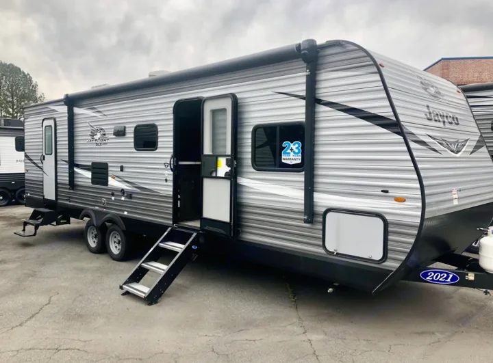 This gray Jayco travel trailer, with its door and steps open, is perfect for RV rental adventures as a spacious camper.. Jayco Jay Flight SLX 2021