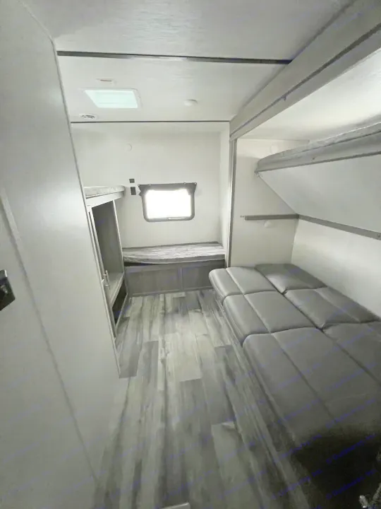 RV rental interior: cozy bunk beds, sofa, & wood-look floor. Ideal for family adventures & comfortable travel.. Crossroads RV Volante 2022