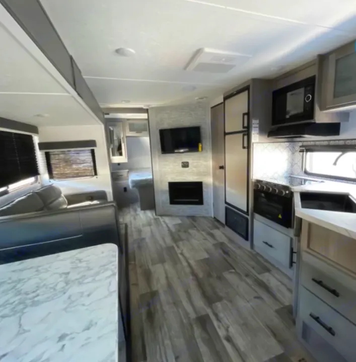View inside a modern RV rental featuring a full kitchen, comfortable living area, dining space, and TV/fireplace.. Coleman light 2022