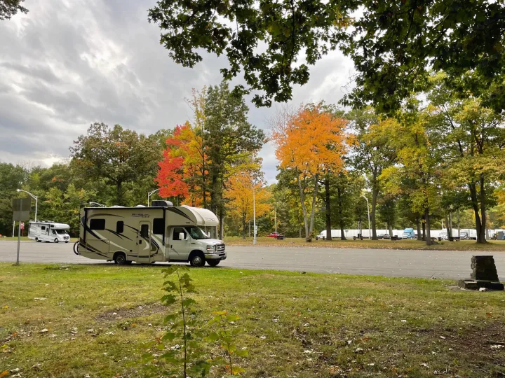 RV rental parked at a colorful autumn rest stop with vibrant fall foliage and cloudy skies, ideal for a road trip.. Thor Freedom Elite 2017