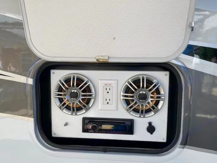 Outdoor entertainment setup in an RV rental featuring speakers, stereo, and power outlets in a side compartment.. Tioga Fleetwood 2011