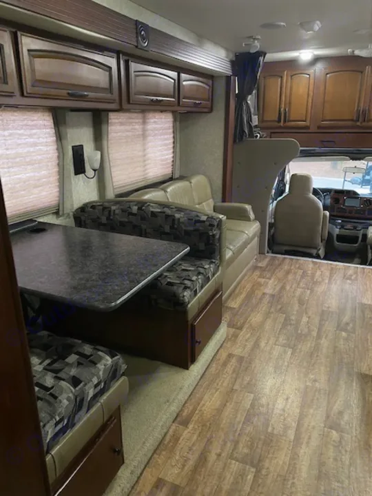 Inside an RV rental: a view of the living area, driver's cockpit, and cabinetry with wood-look flooring.. Tioga Fleetwood 2011