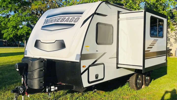 Bright white Winnebago travel trailer with a slide-out extended, parked on grass. Your next RV rental adventure awaits!. Winnebago Micro Minnie 2021