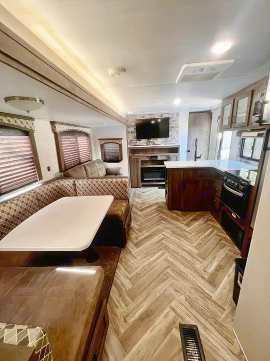 This RV rental showcases a full kitchen, dining booth, and living area with TV & fireplace, all with modern finishes.. Forest River Evo 2020