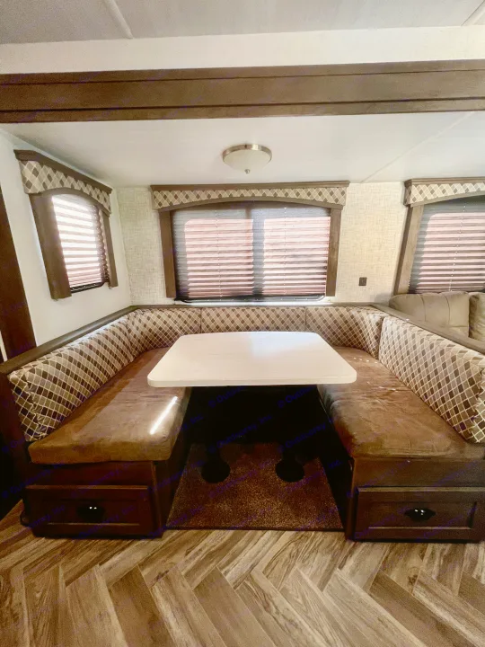 Cozy RV rental dinette: U-shaped seating, light table, blinds, and herringbone floor, offering comfort for travelers.. Forest River Evo 2020