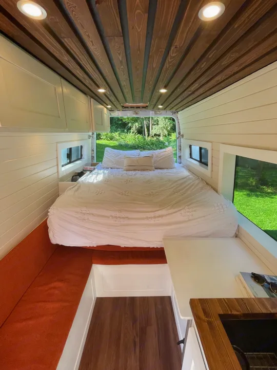 Bright RV rental interior featuring a large bed, full kitchenette, and comfortable seating in a well-designed camper van.. Mercedes Sprinter 2013