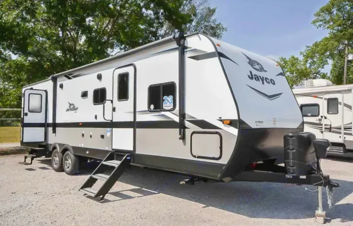 A modern white & grey Jayco travel trailer, an ideal RV rental, parked with extended steps for easy access.. Jayco Jay Flight 2022