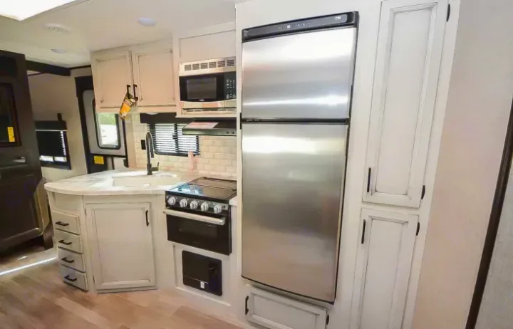 RV rental with a modern kitchen interior: stainless steel fridge, stove, microwave, and sink with white cabinets.. Jayco Jay Flight 2022